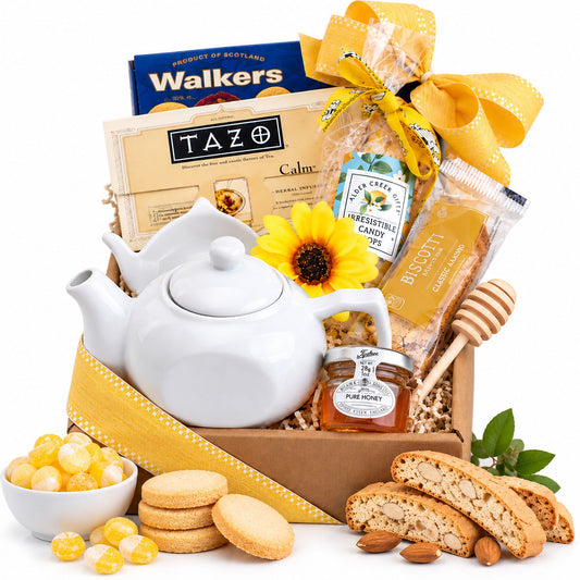 Tea gift basket with white ceramic teapot, honey jar, biscuits, cookies, and sweets