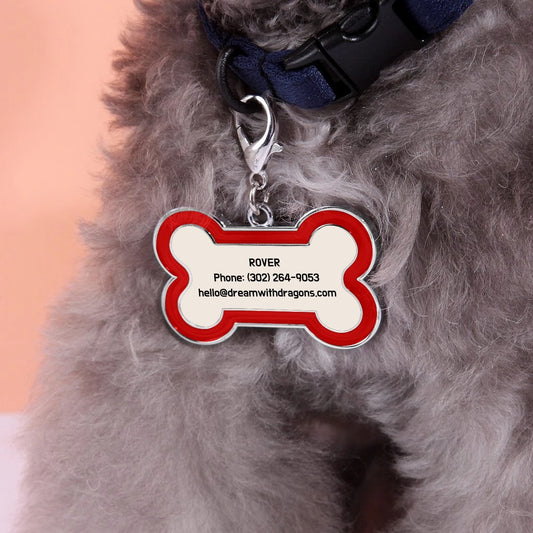Red bone-shaped dog tag keychain with metal ring on gray pet fur