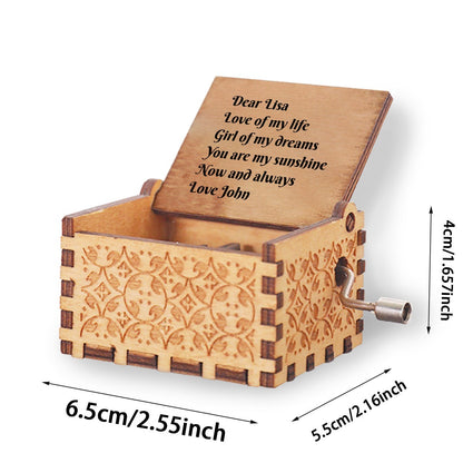 Engraved wooden music box with open lid, engraved message, and crank handle