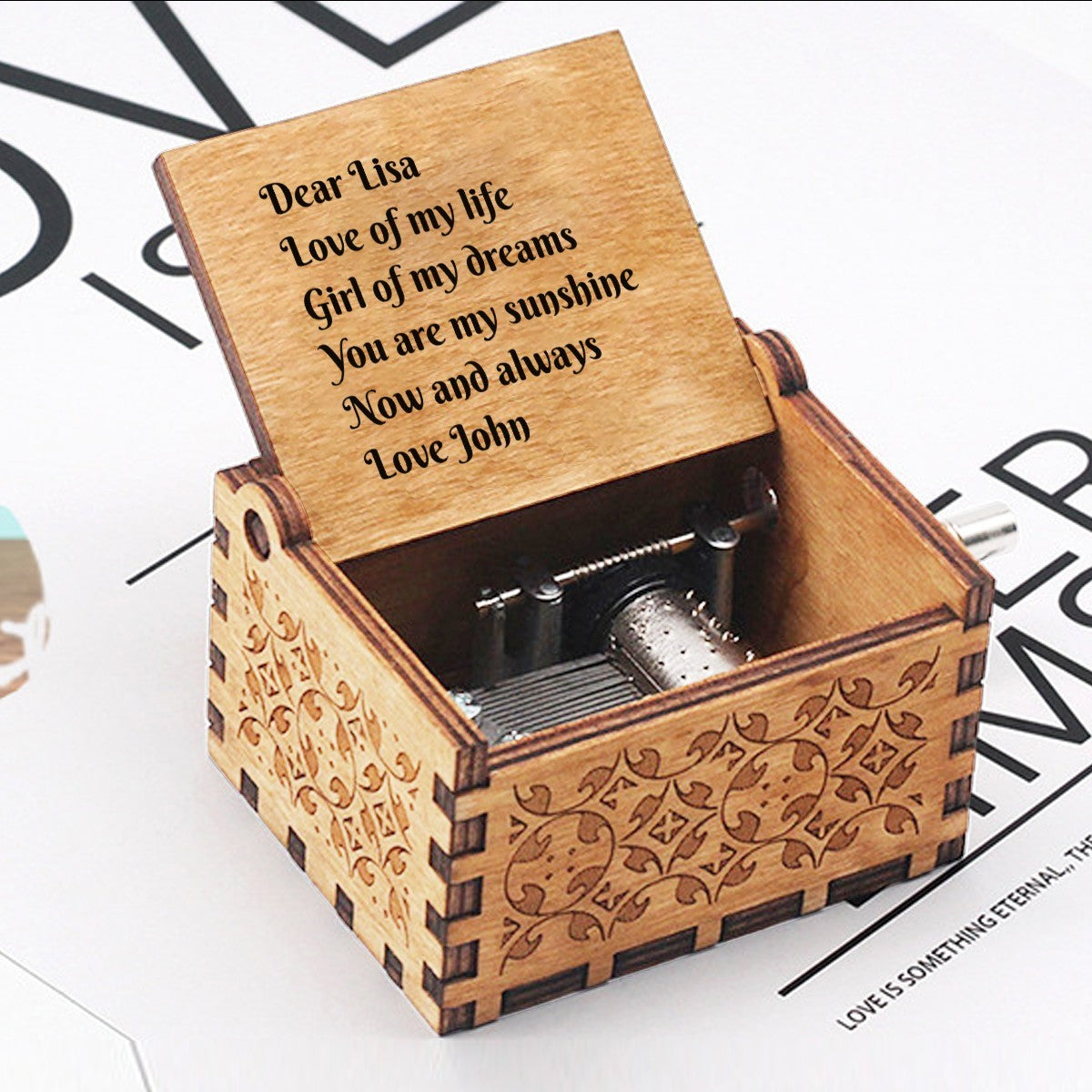Engraved wooden music box open with visible mechanism and message panel on lid