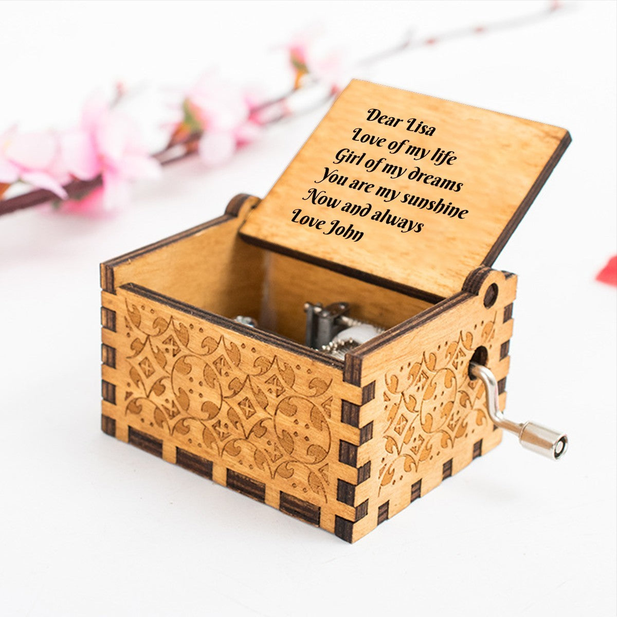 Engraved wooden music box with open lid, carved floral sides, and crank handle