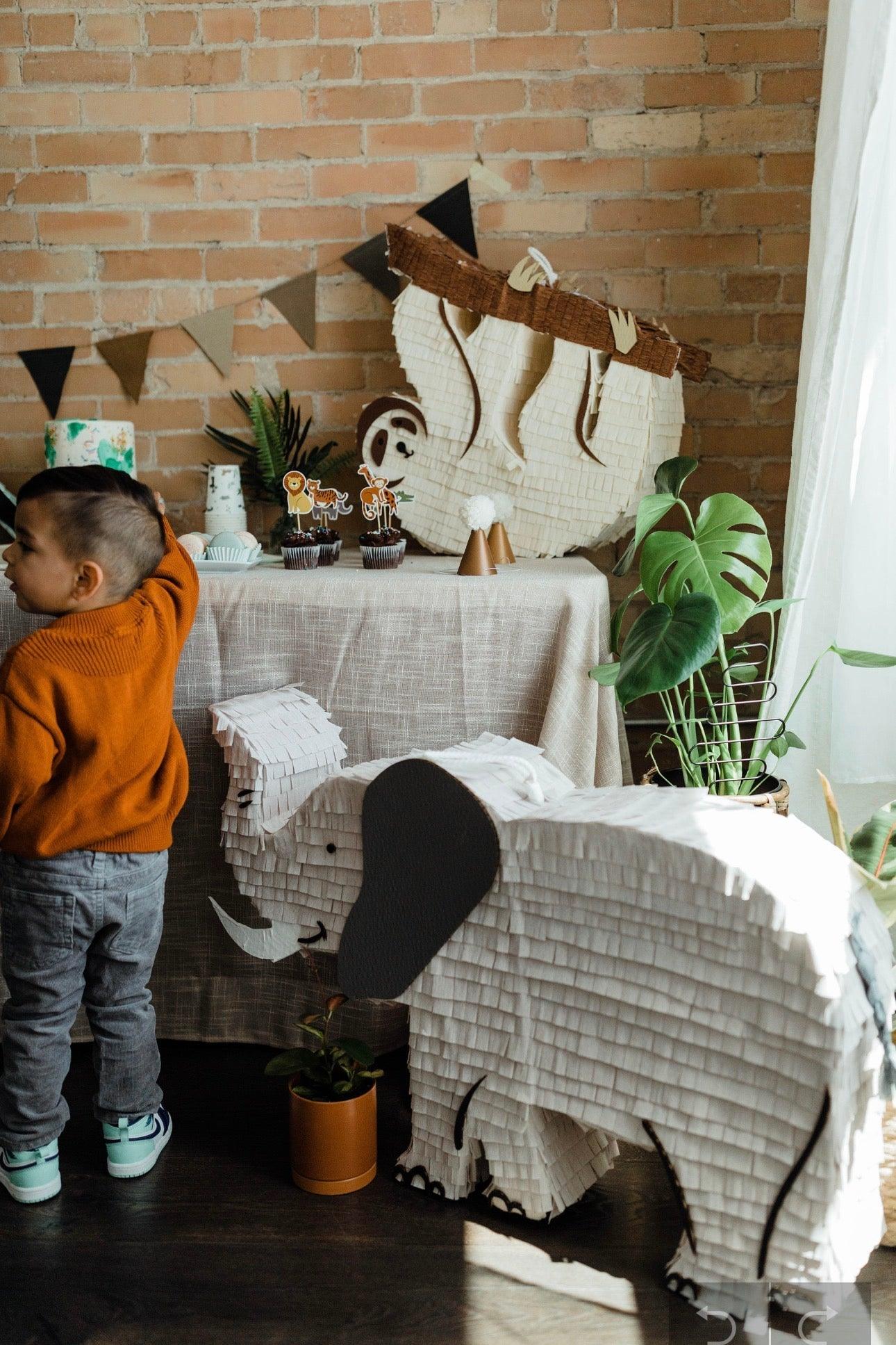 Piñata de elefante blanca con orejas negras y colmillos, sombrero de yute en la cabeza
