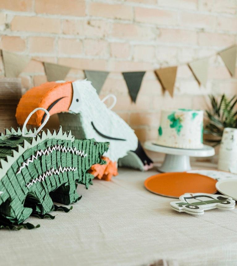 Tropical toucan piñata on party table, orange beak and white body with handle loop