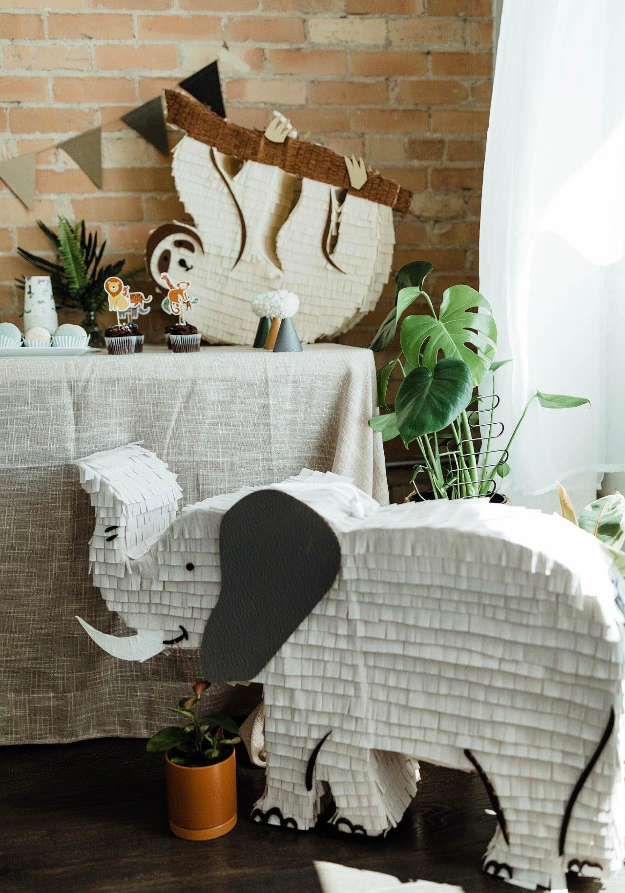 Piñata elefante blanca con orejas grandes negras y colmillos, guirnalda de yute en el lomo