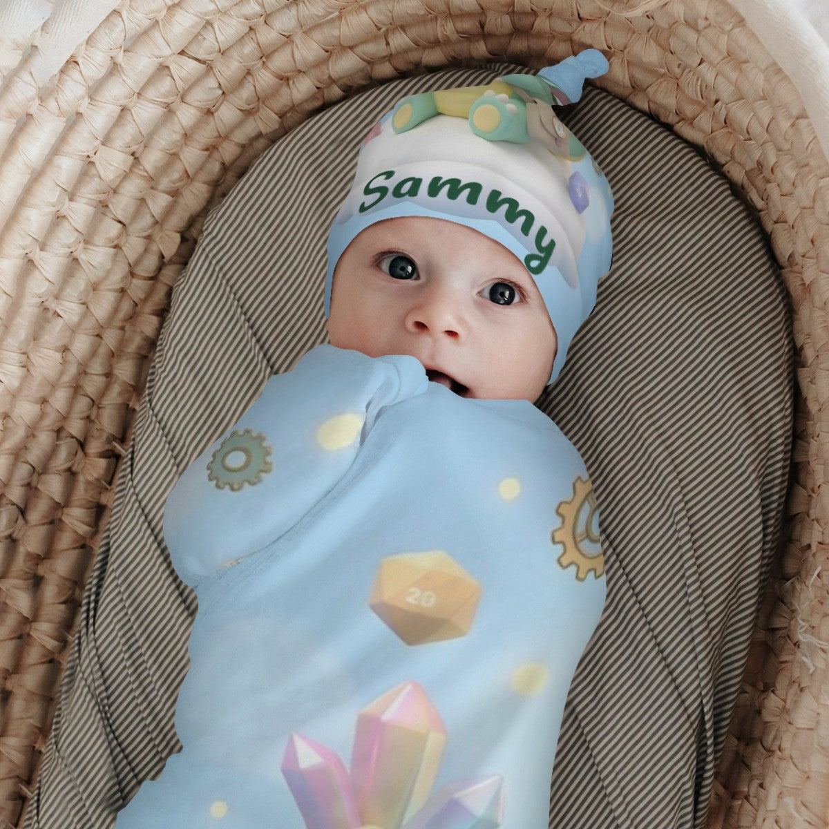 Newborn swaddled in blue dragon print blanket with 'Sammy' green dragon hat.