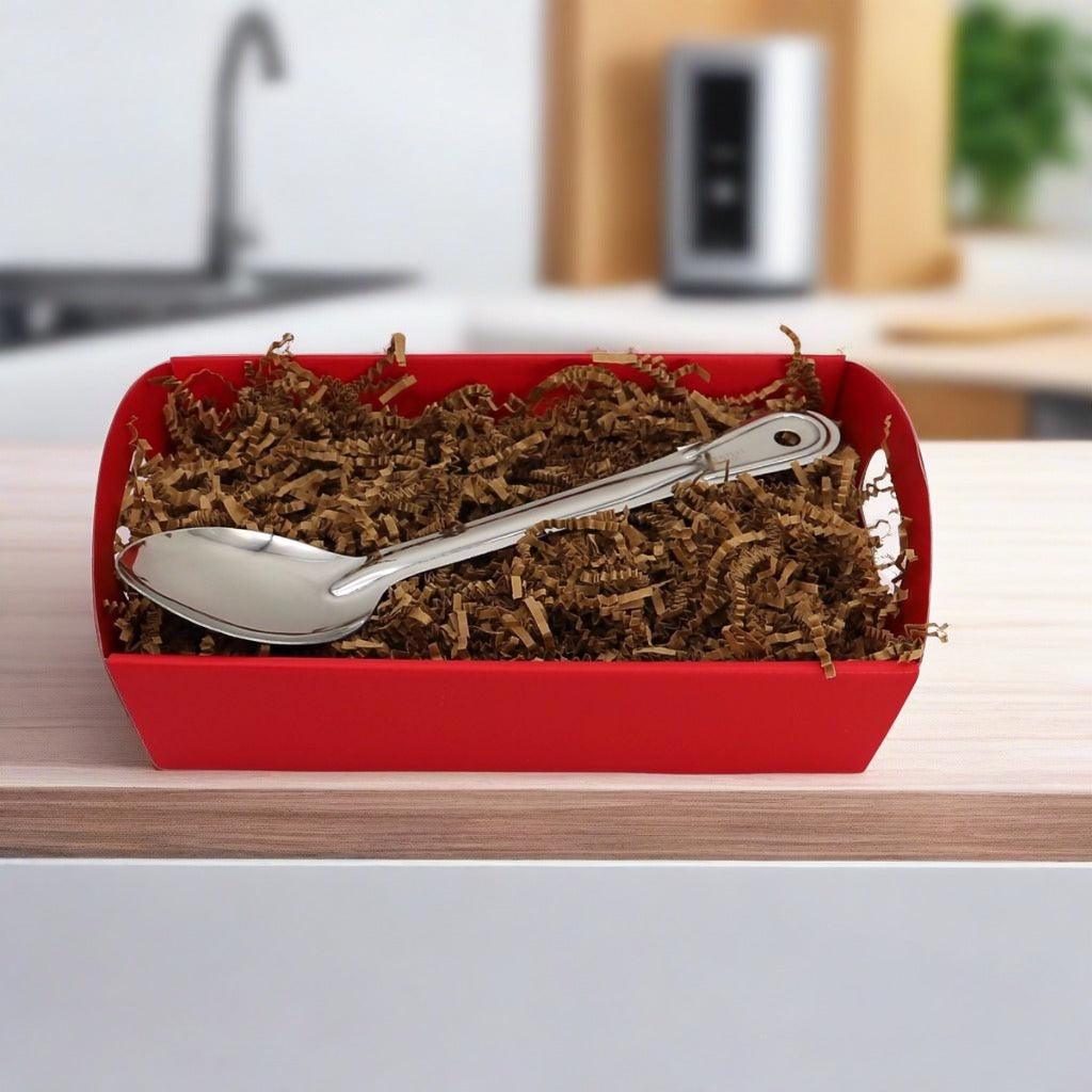 Red gift basket with metal serving spoon and brown shredded filler