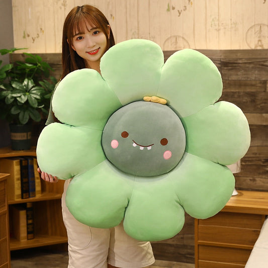 Mint-green plush flower pillow with round gray face, smiling details, and pink blush cheeks