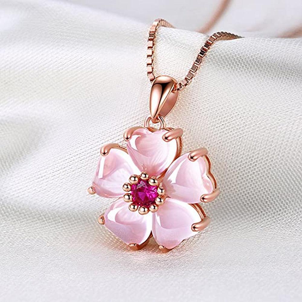 Rose-gold sakura pendant necklace with pink flower petals and fuchsia center stone.