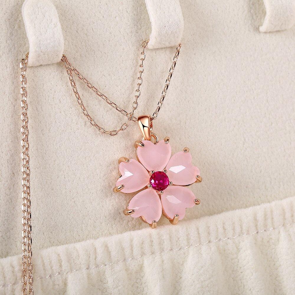 Rose-gold sakura pendant necklace with pink flower pendant and fuchsia center stone.