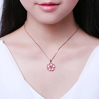 Rose-gold sakura pendant necklace worn at collar, pink flower with fuchsia center.