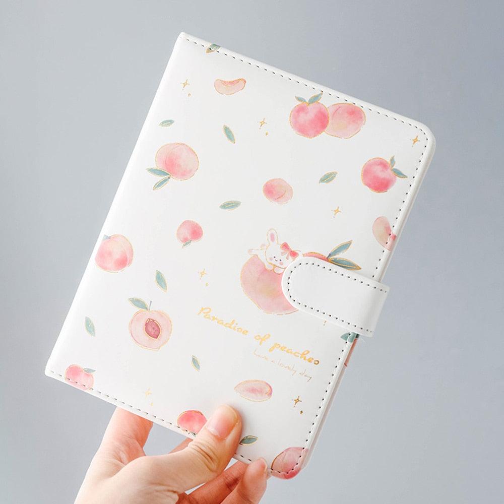 Peach-themed notebook with fruit pattern, side strap, stitched corners, and a small bunny graphic