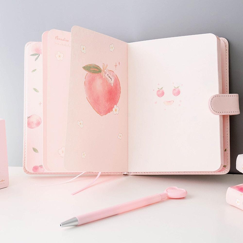 Peach notebook opened flat, showing interior pages and a front cover with peach illustration
