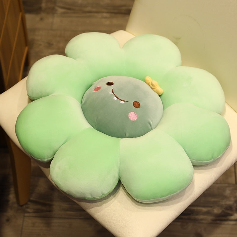 Light green plush flower pillow with gray animal face, stitched smile, and pink cheek accents
