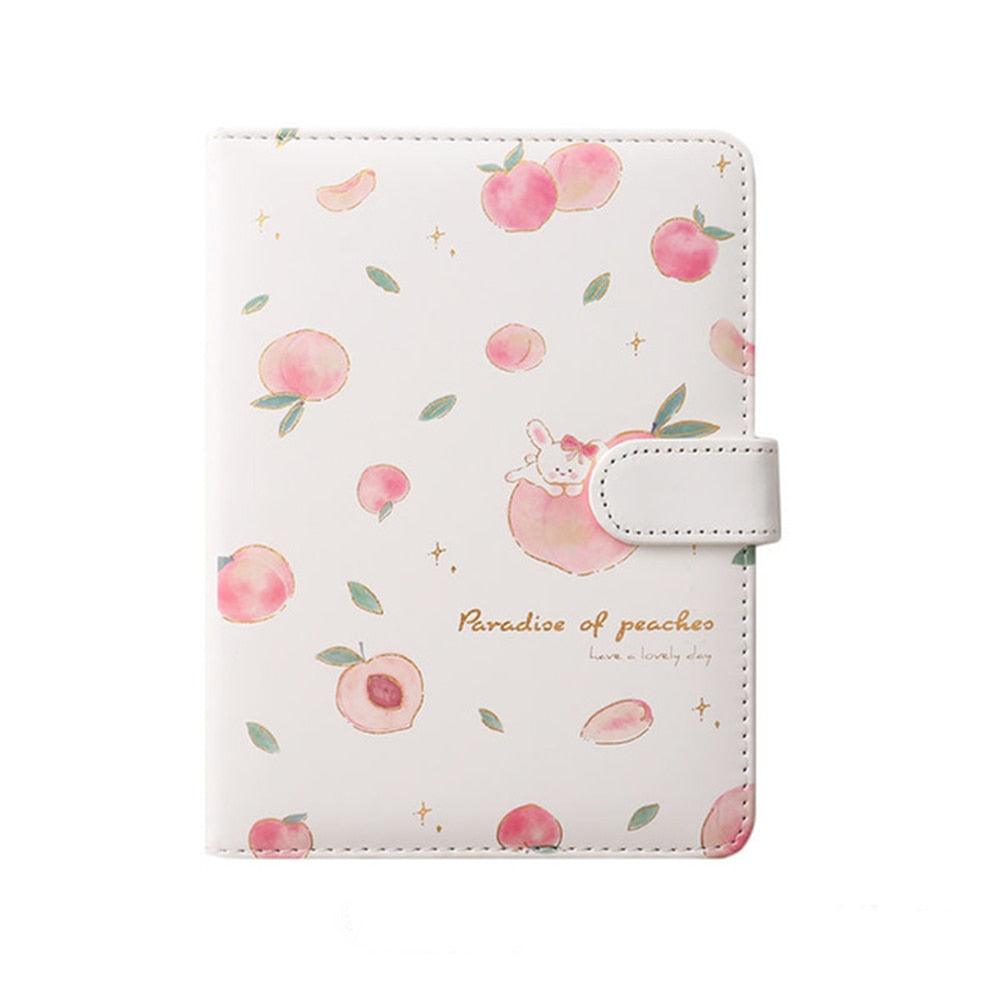 White and pink peach notebook cover with scattered fruit illustrations and a side strap