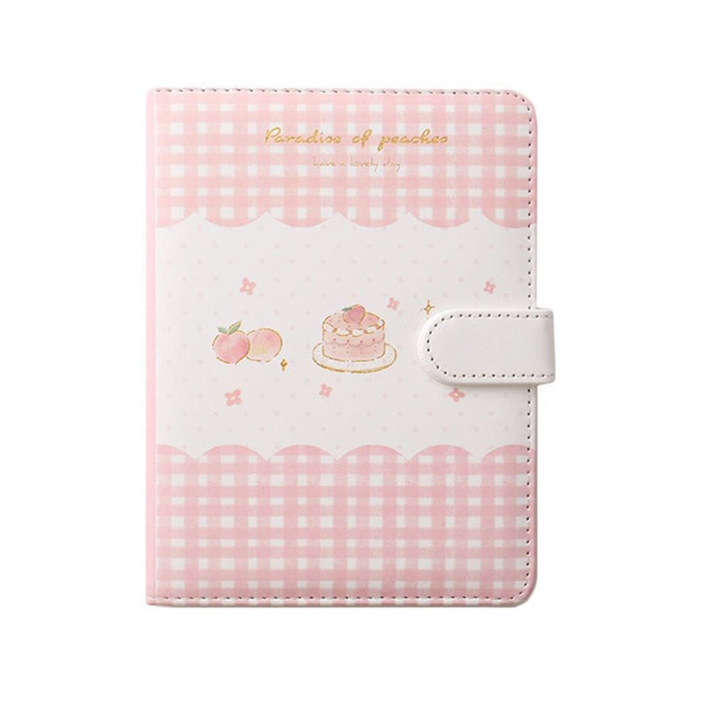 Peach-themed notebook cover with pink gingham border, cake and peach graphics, and strap