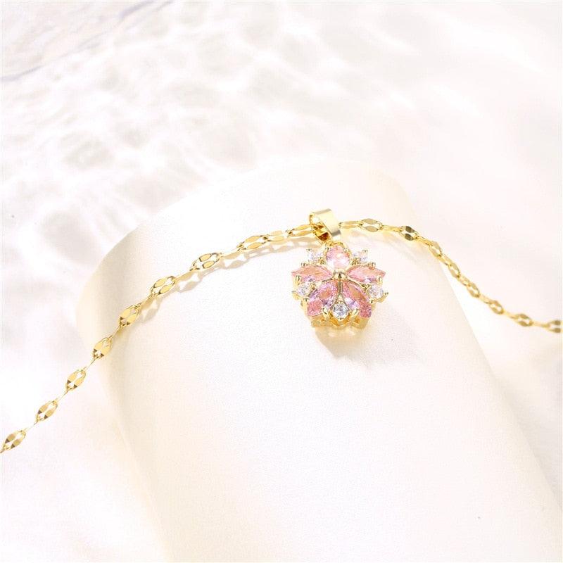 Gold-tone chain necklace with small cherry blossom pendant featuring pink and clear crystals
