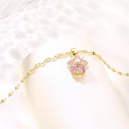 Gold-tone chain necklace with small cherry blossom pendant featuring pink and clear crystals
