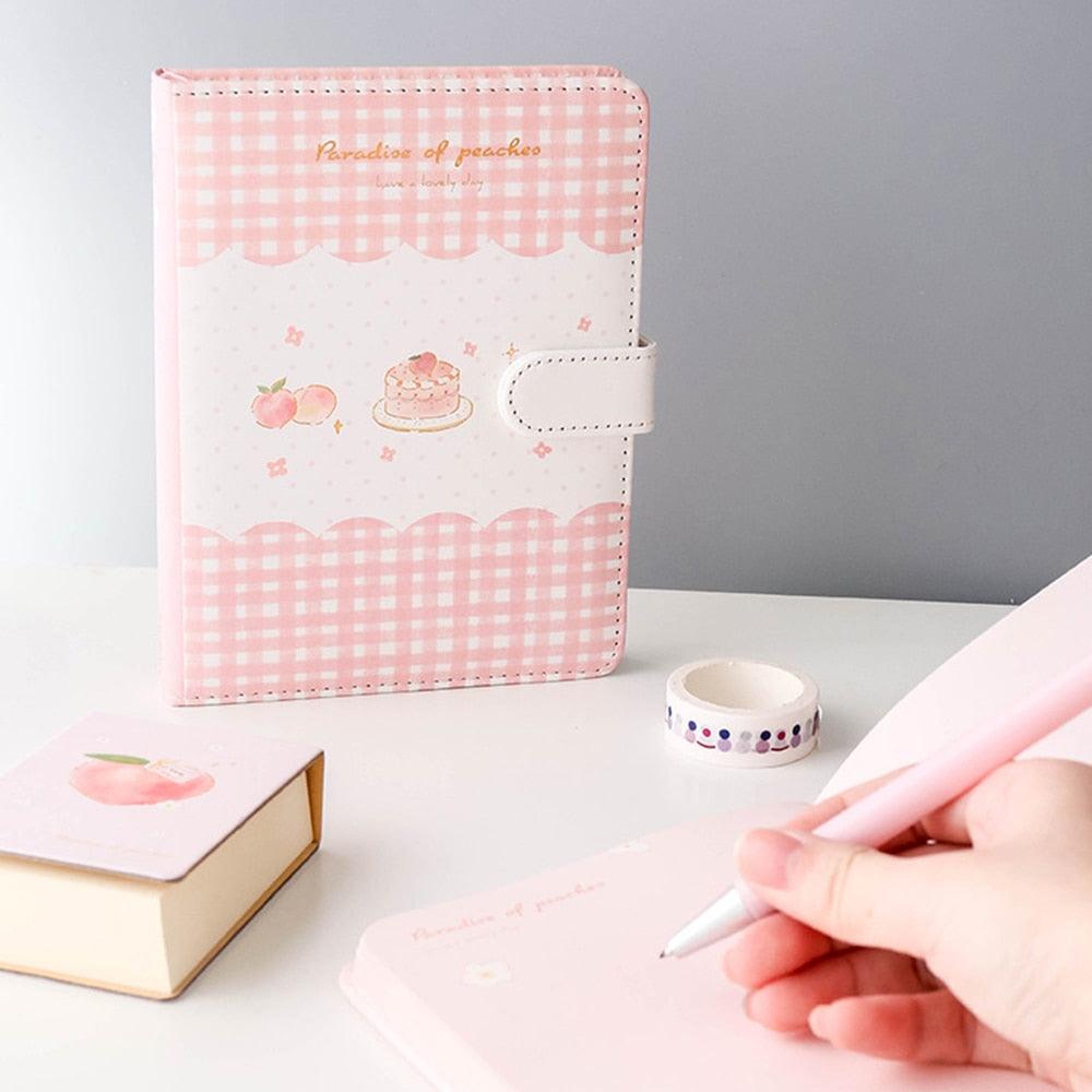 Pink gingham notebook with peach, cake, and flower icons, front strap closure