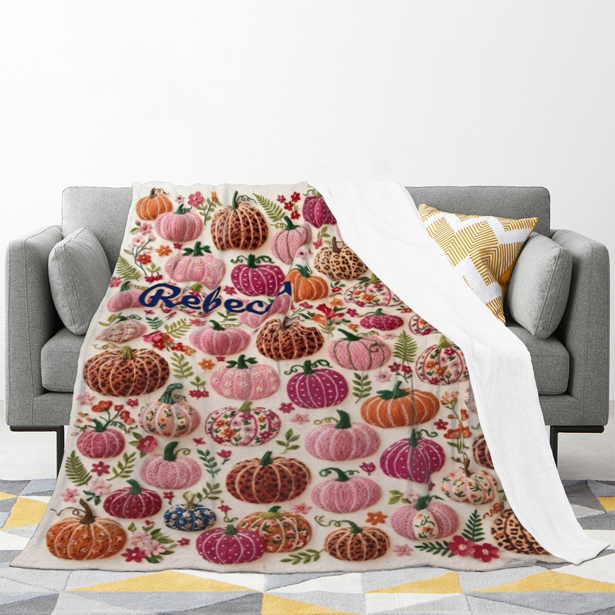 Personalized Halloween fleece throw blanket with pumpkin-floral pattern, draped on gray sofa