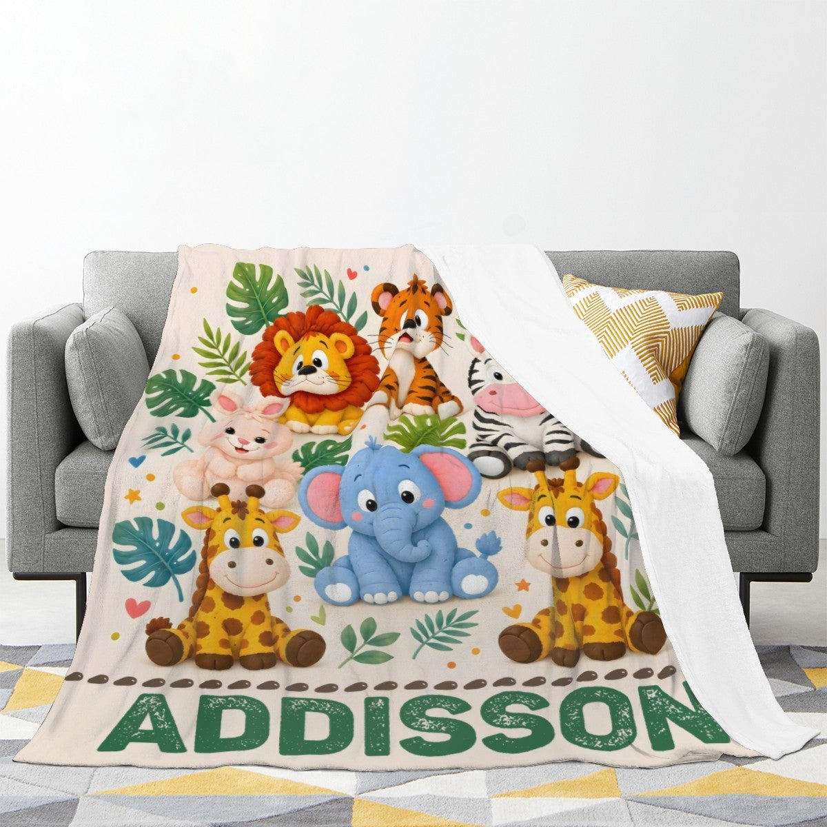 Personalized safari name blanket draped on a couch, cream with safari animals and ADDISON