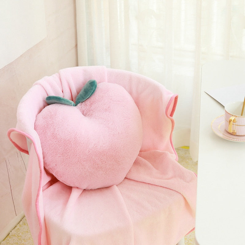 Pink plush peach pillow with green leaves and draped blanket