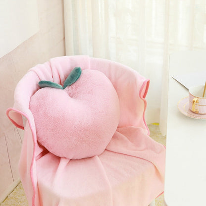 Pink plush peach pillow with green leaves and draped blanket