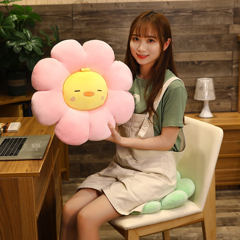 Pink plush flower pillow with yellow beak-like chick face and small raised petal shapes