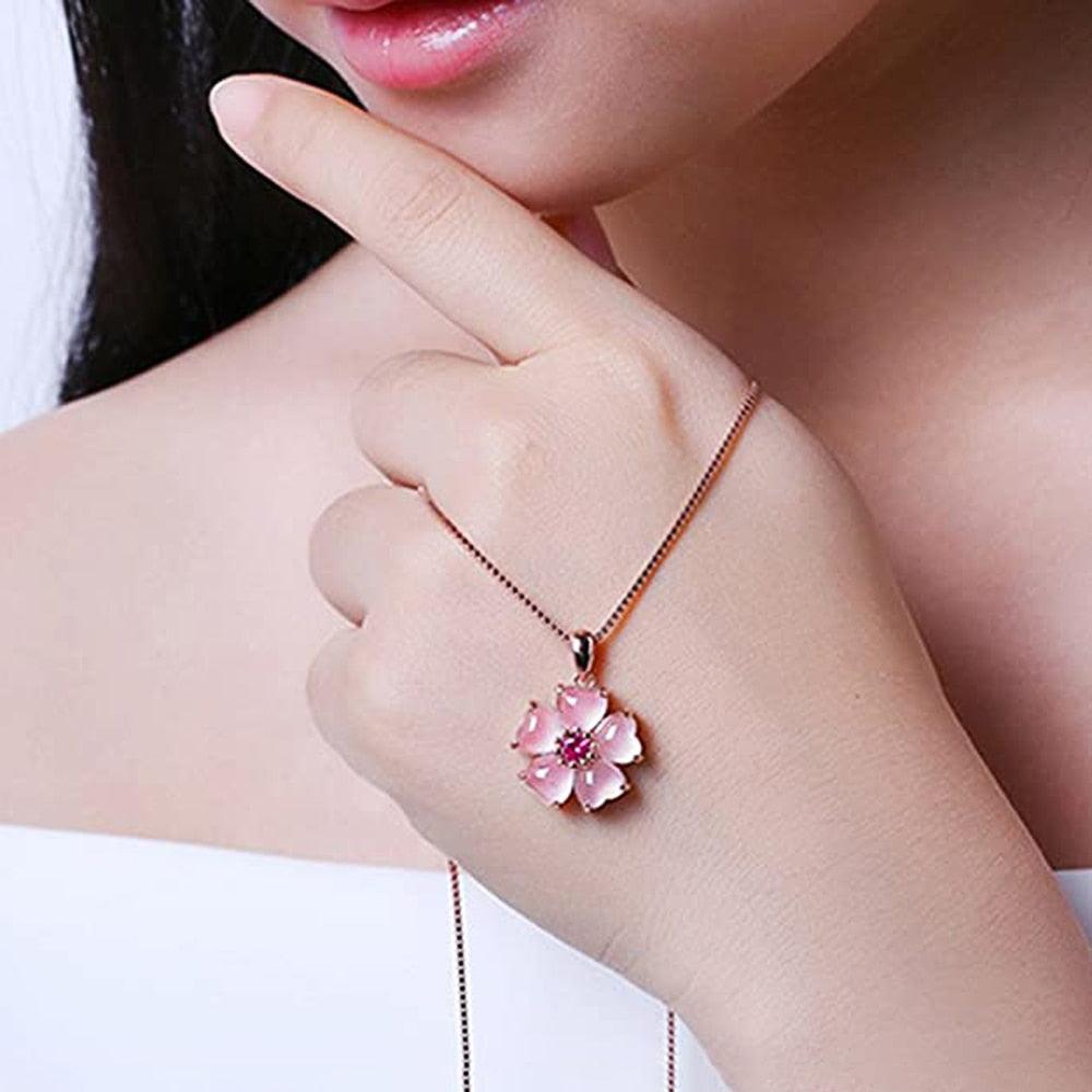 Rose-gold chain necklace with small pink sakura flower pendant and fuchsia center.