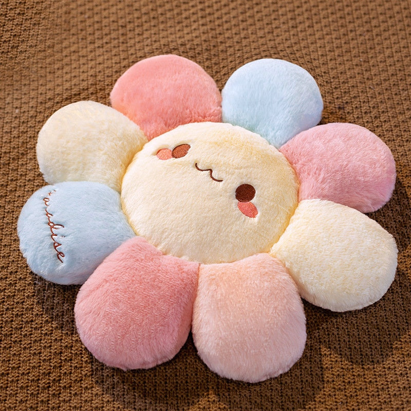 Soft plush flower pillow with embroidered smile and pastel petal segments