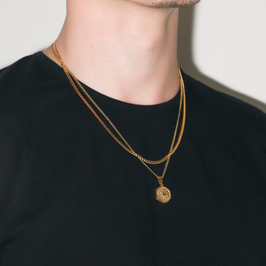 Gold-tone compass pendant with hammered face on Cuban link chain, layered look