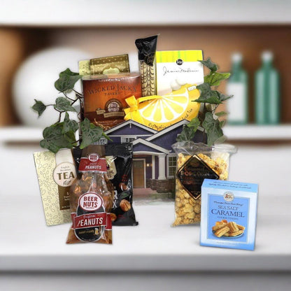 Gift basket close-up with house-shaped box and snacks: tea, peanuts, caramel crackers