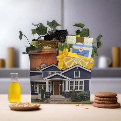 Gift basket with house-shaped container; snacks and crackers on table, bottle nearby