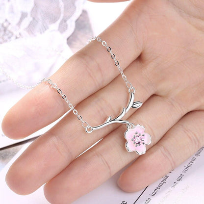 Cherry blossom pendant necklace in silver worn on hand, pink flower charm centerpiece
