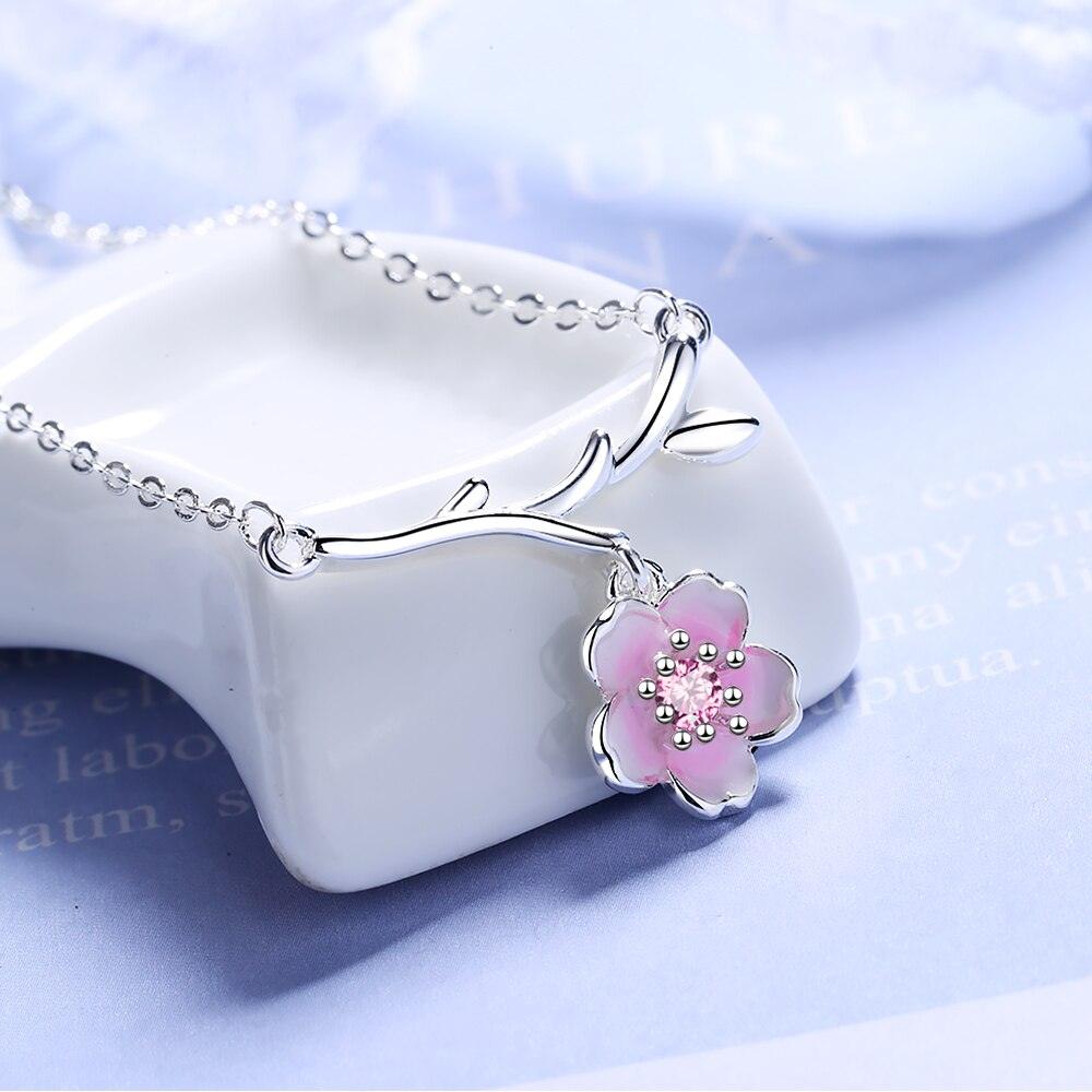 Silver necklace with pink cherry blossom pendant and small heart-like charm detail
