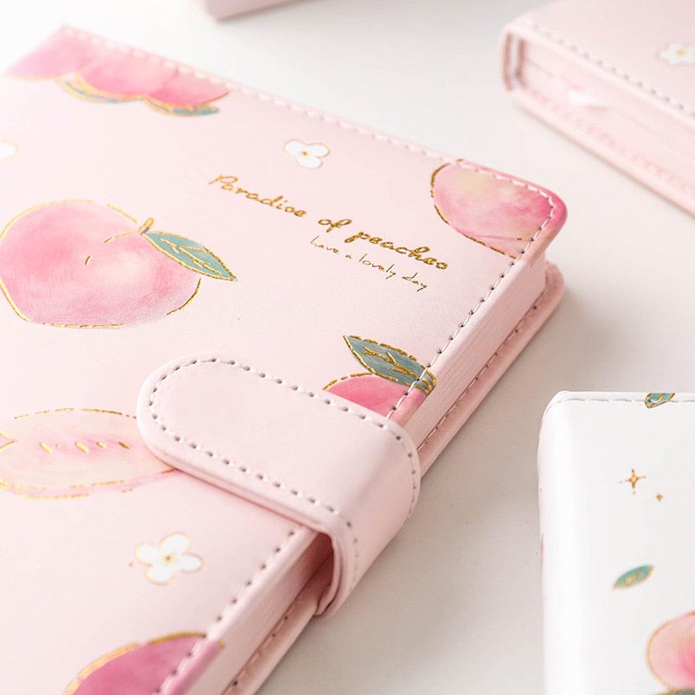 Pink notebook cover with peach prints, stitched corners, and snap-style closure tab