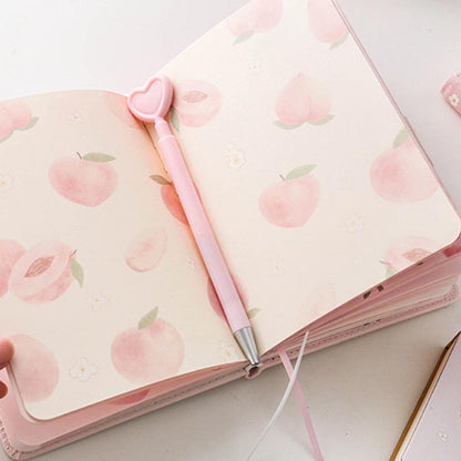 Pink notebook open to peach-pattern pages, with a pink pen and heart-shaped cap