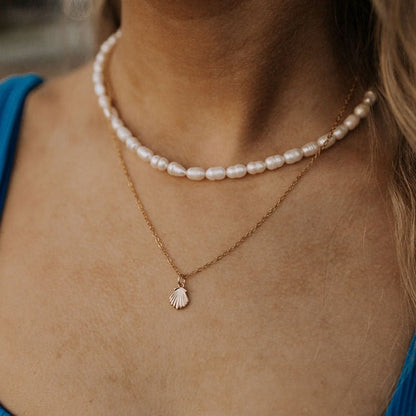 Gold shell pendant necklace layered with a white pearl strand
