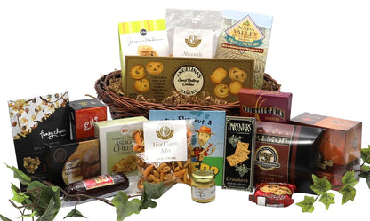 Wicker gift basket filled with assorted snacks and gourmet treats with decorative greenery