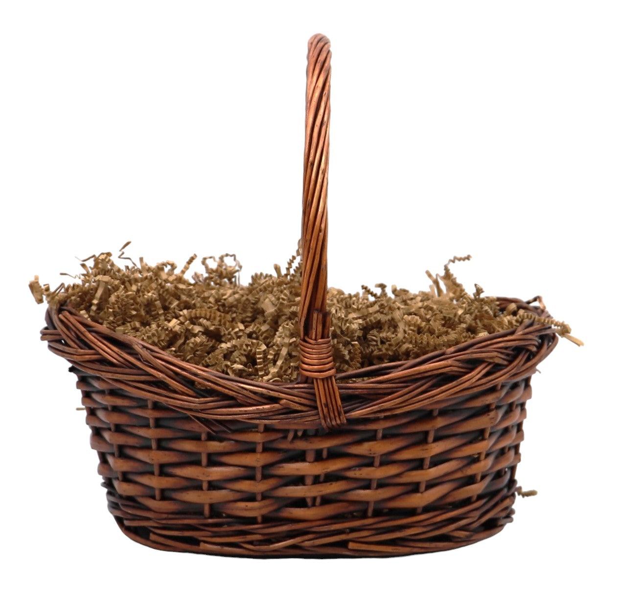 Wicker gift basket with handle, filled with tan shredded filler