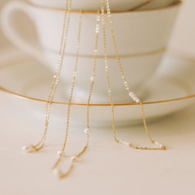 Gold-tone necklace with small white pearls spaced along the fine chain