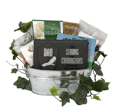 Silver metal gift tin filled with assorted cookies and nuts, topped with decorative greenery