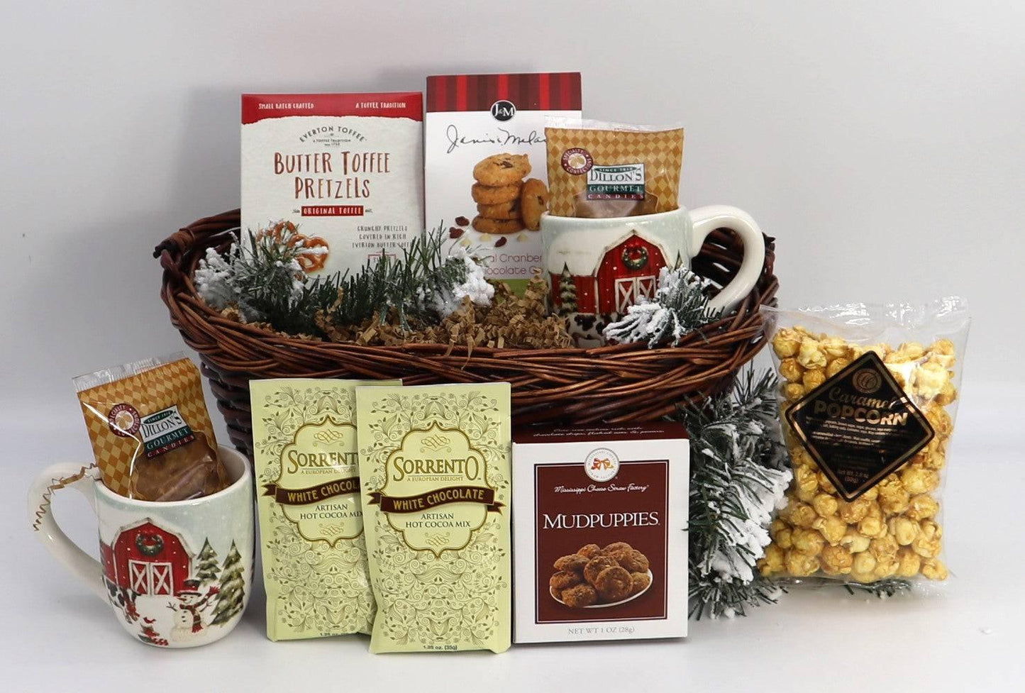 Wicker gift basket with barn mugs, hot cocoa, popcorn, candy, and faux pine with snow