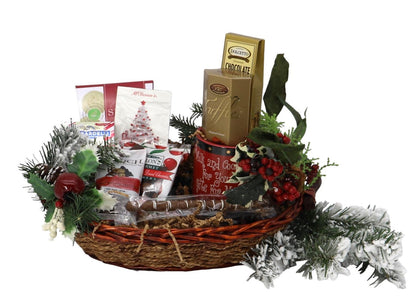 Wicker Christmas gift basket with assorted chocolates, cookies, and holiday greenery