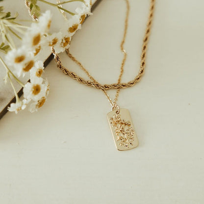 Gold-tone necklace with a raised floral pendant and twisted chain