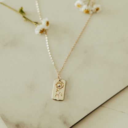 Gold chain necklace with a rectangular sunflower pendant shown flat