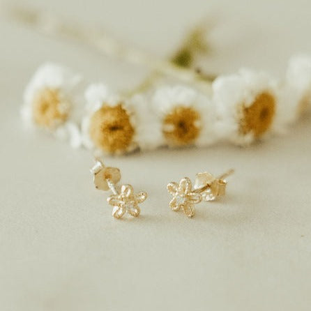 Pair of gold flower stud earrings with openwork petals and visible post backs.