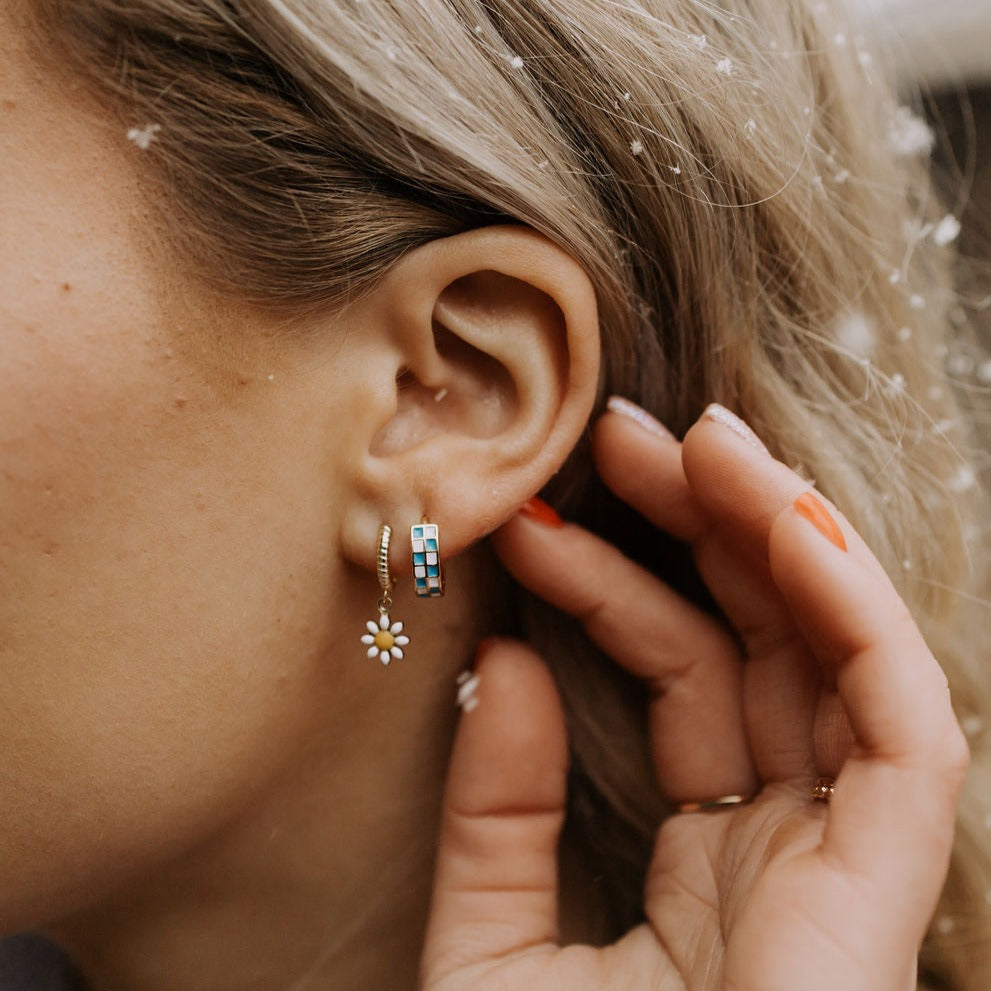 Blue and white checkered hoop earring worn in an ear