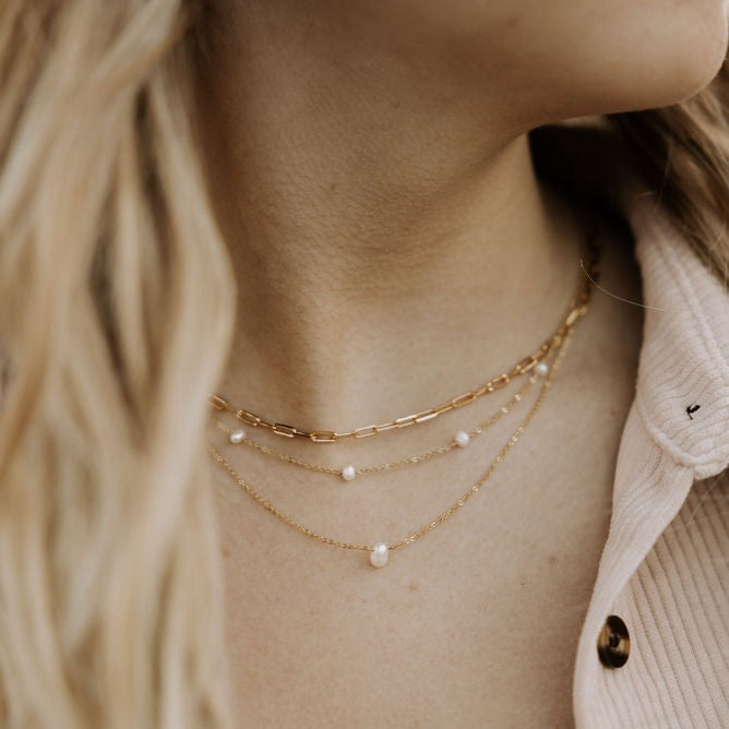 Gold-filled paperclip necklace worn with layered pearl chains.