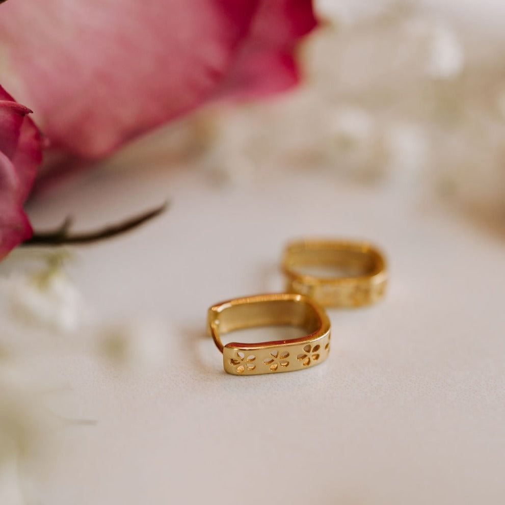 Gold hoop earrings shown with floral details facing outward