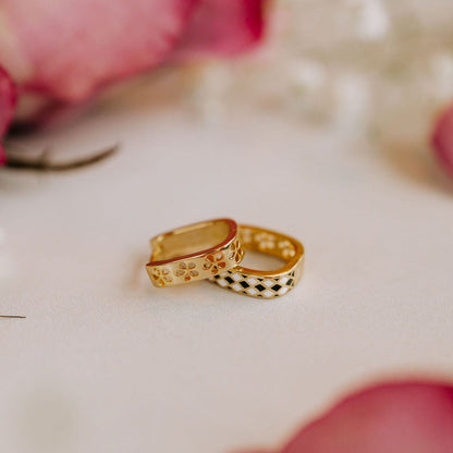 Pair of gold reversible hoops, one with floral details and one with a black-and-white diamond pattern